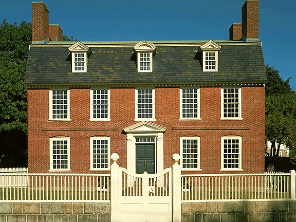 Federal period three-story brick house with four chimneys and a large white gate in front