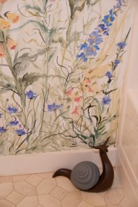 large wooden snail in bathroom with hand-painted garden mural